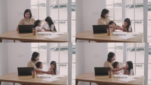 亚洲妇女视频通话笔记本电脑，同时照顾她的女儿在家里高清在线视频素材下载
