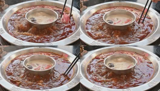 人们用筷子将肉放入辛辣的中国火锅的特写。高清在线视频素材下载