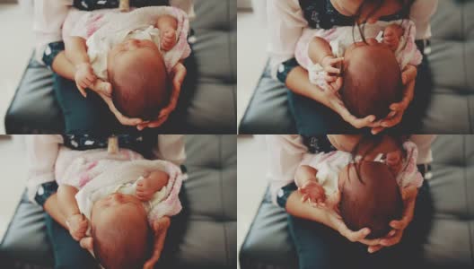 年轻的母亲抱着并亲吻她的新生婴儿高清在线视频素材下载