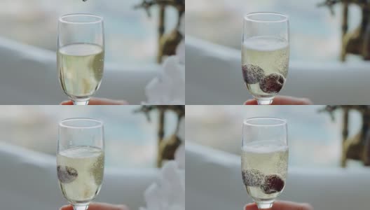 两颗樱桃在慢镜头中美妙地落入一杯葡萄酒中。冷却鸡尾酒高清在线视频素材下载
