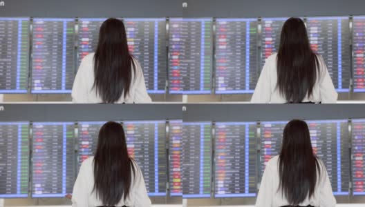 在国际机场的候机楼里，一个留着黑色长发的女商人正拿着泰国护照，看着信息板，查看她的航班和背景模糊的航班时间表。高清在线视频素材下载