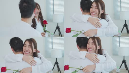 亚洲青年惊喜送玫瑰给美丽的女友。迷人浪漫的新婚男女坐在床上，一起享受庆祝周年纪念日和情人节高清在线视频素材下载