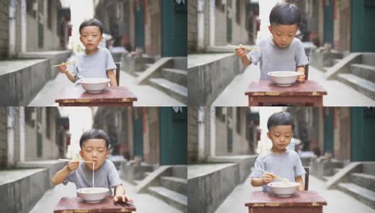 快乐的亚洲孩子用筷子吃美味的面条高清在线视频素材下载
