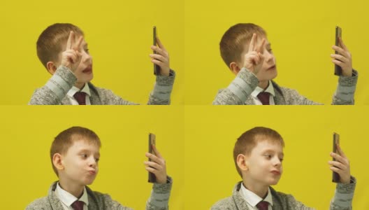一名7-8岁的白人男孩兴高采烈地拿着智能手机自拍。一名男生在摄影棚里自拍。回到学校。有趣的学校的记忆。高清在线视频素材下载