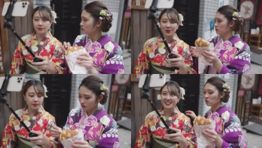 年轻的女性朋友穿着和服在街上吃面包，为了拍视频高清在线视频素材下载