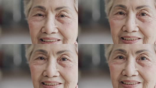 4K近景拍摄，一名80多岁的亚洲老年女性(80多岁)，头发花白，脸上带着快乐的表情和美丽的眼睛，对着镜头微笑，享受着退休生活。高清在线视频素材下载