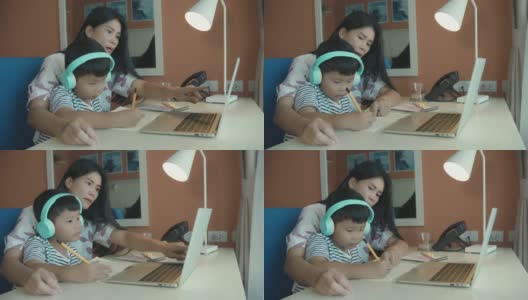 亚洲母亲教和解释家庭作业的孩子在线学习期间在家教育，概念在线学习高清在线视频素材下载