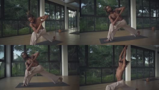 男子练习旋转弓步瑜伽姿势在工作室在日出快速慢动作高清在线视频素材下载