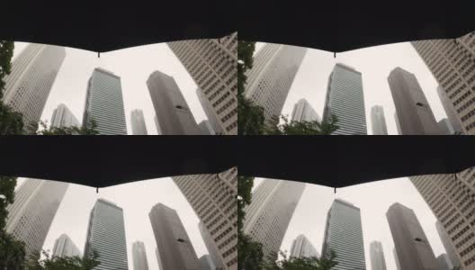 下雨天，撑着伞仰望摩天大楼高清在线视频素材下载