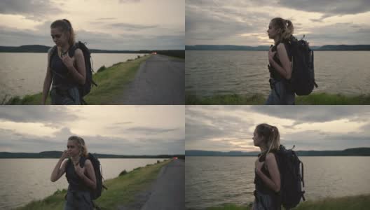场景中年轻可爱的背包女享受沿着湖边散步，女人放松，快乐时光高清在线视频素材下载