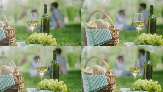 公园里的白葡萄和一瓶白葡萄酒，背景是一对浪漫的情侣高清在线视频素材下载