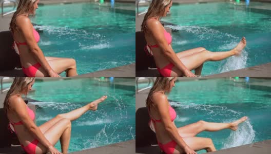穿着比基尼的女人顽皮地踢她的脚在游泳池的水高清在线视频素材下载