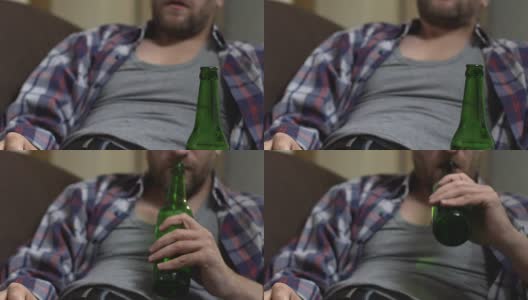 醉鬼大胡子坐在沙发上喝啤酒，上瘾，下视高清在线视频素材下载