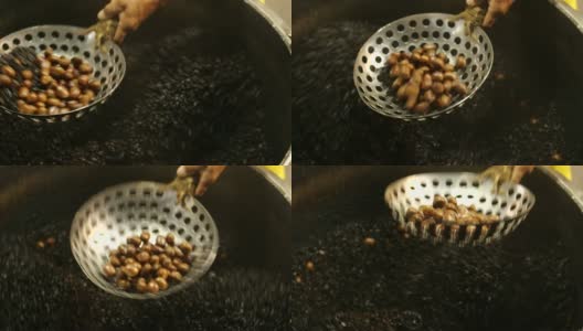 亚洲男人的手把栗子放在锅里，放在漏勺上。(特写)在泰国，用大平底锅烤栗子和咖啡豆。高清在线视频素材下载