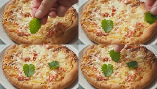 在家做披萨。把薄荷叶铺在新鲜烤好的玉米饼上，配上番茄和奶酪。高清在线视频素材下载