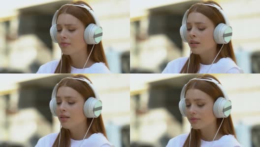 哭泣的少女在户外戴着耳机听音乐高清在线视频素材下载
