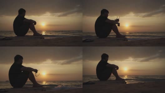 亚洲男子沮丧和坐在海滩日落，芭堤雅高清在线视频素材下载