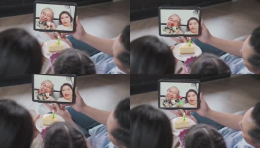 亚洲年迈的祖父母在社交距离中通过视频电话在家庆祝虚拟生日，感受被爱和快乐，由家人和侄子准备蛋糕。新标准的概念。高清在线视频素材下载