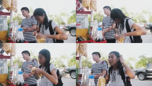 快乐的亚洲女孩和她的兄弟一起在当地街头的食品推车上买零食，生活方式的概念。高清在线视频素材下载