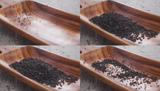 黑芝麻掉进乡村木制厨房用具的慢动作。在粗糙的黄麻垫子上高清在线视频素材下载