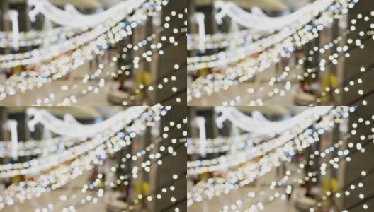 室内天花板上挂着夜光灯泡。这些装饰品在圣诞节时使用。模糊的背景是人们进入或离开建筑。的焦点。在看。高清在线视频素材下载