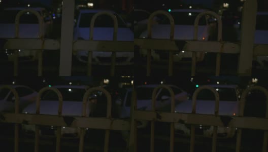 在大都会地区的夜晚，在前景有栅栏的停车场上平移高清在线视频素材下载