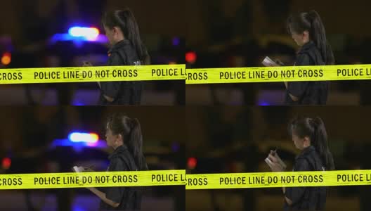 女亚裔美国女警察记录在犯罪现场与闪烁的警车警报器在背景高清在线视频素材下载