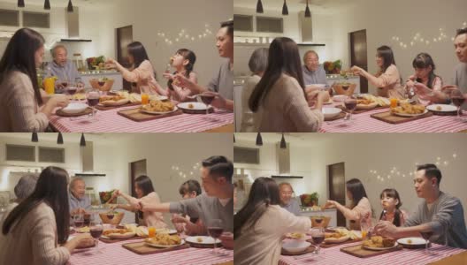 幸福的家庭时间和关系，亚洲大家庭有一个小聚会，一起在家里吃东西。爷爷很高兴看到他的孩子和侄子在家里的餐桌上吃饭，分享食物。高清在线视频素材下载
