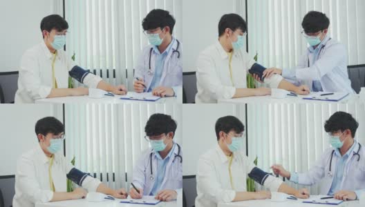 一名亚洲医生在做年度检查时使用病人的血压监测器，并解释他的血压。高清在线视频素材下载