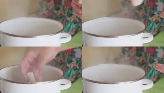 一位妇女将蓝莓饺子放入沸水中。蒸汽从锅里冒出来。特写镜头。高清在线视频素材下载