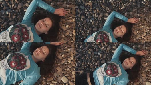 在一个甜蜜的镜头中，漂亮的女人面带微笑躺在岩石海滩上高清在线视频素材下载