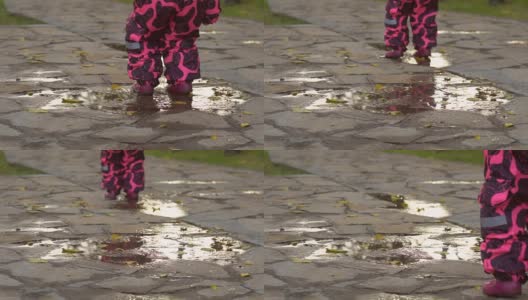 漂亮的小女孩穿着温暖的粉色工装裤跑过水坑。高清在线视频素材下载