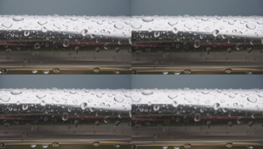 不锈钢扶手上的雨滴映衬着模糊的大海背景。特写镜头。雨露的水滴聚集在闪闪发光的铬钢杆扶手上高清在线视频素材下载