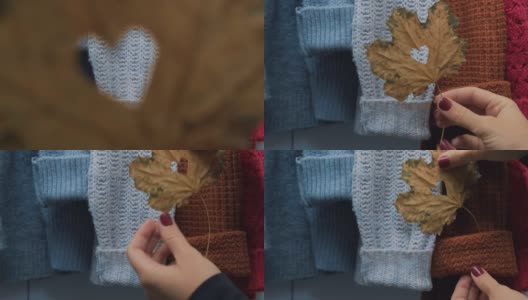 秋天的概念。女性将枫叶放在温暖舒适的毛衣上，做成心形。针织羊毛衫和马海毛毛衫。Hygge风格高清在线视频素材下载
