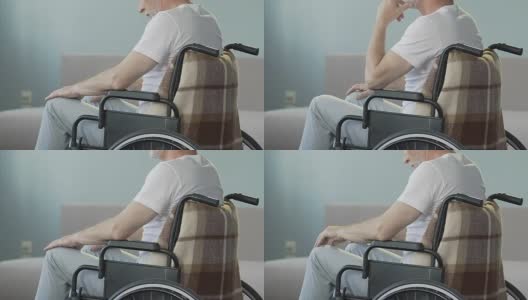 一位坐在轮椅上看着双腿点头的老人，失去了行走的能力高清在线视频素材下载