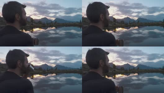 夏日户外，日出日落时分，在山湖边，年轻的成年男子用金属杯喝茶高清在线视频素材下载