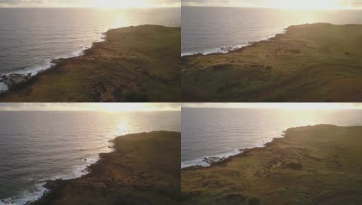空中镜头。日出时，无人机在复活节岛悬崖上拍摄。在一个充满色彩的多云的日子里，太平洋撞击海岸线和太阳从地平线上升起的令人惊叹的景色高清在线视频素材下载