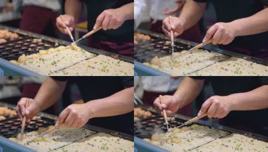 在日本街头小吃市场，厨师用章鱼烧锅烹饪日本小吃章鱼烧。男子准备混合传统日本肉丸与甜酱吃。高清在线视频素材下载