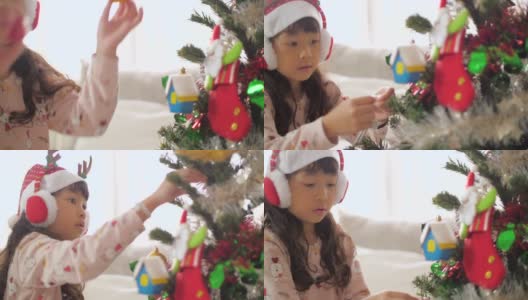 小女孩在圣诞节用装饰品装饰圣诞树高清在线视频素材下载