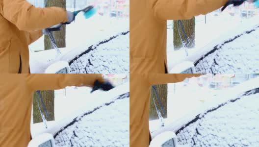 一名男子在雪后从车上刷雪。一只穿着芥末色夹克的手，白色的身体上放着汽车扫把。冬天的天气条件。慢动作高清在线视频素材下载