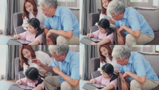 亚洲的祖父母和孙女在家用平板电脑画画。高三的中国，爷爷奶奶和小女孩躺在客厅的沙发上，开心地度过家庭时光，放松心情。缓慢的运动。高清在线视频素材下载