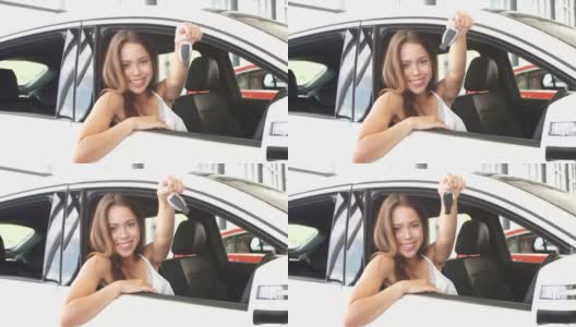快乐的白人年轻女司机坐在白色的车展示汽车展厅的车钥匙高清在线视频素材下载