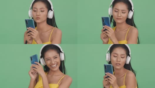 亚洲美女听音乐在线和幸福的情绪微笑。女人戴着耳机，拿着智能手机。美的概念，时尚和音乐体验。高清在线视频素材下载