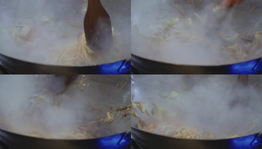 厨师将乌冬面与炒好的蔬菜在热锅里混合高清在线视频素材下载