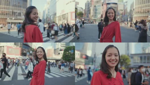 Young woman in red dress standing on Shibuya crossing, looking at camera高清在线视频素材下载
