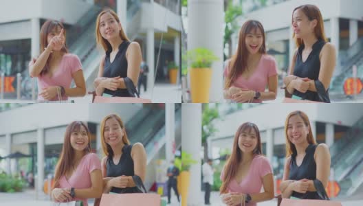 两位快乐的亚洲年轻女性在百货商店的户外购物在销售季节在年底。女孩们拿着购物袋，快乐地走着，微笑着一起买东西高清在线视频素材下载