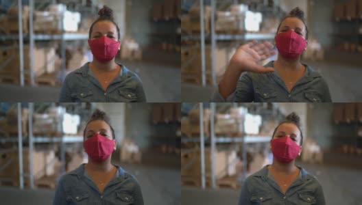 一个戴着面罩的女人在一个配送仓库里进行商业视频通话-从摄像头角度高清在线视频素材下载