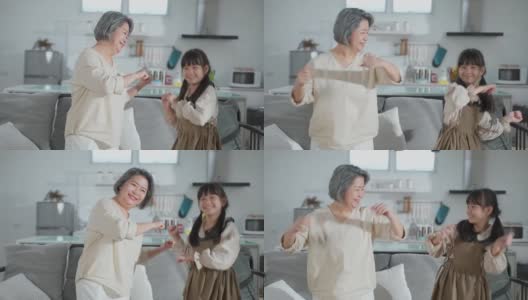 亚裔家庭小女孩和爷爷奶奶在客厅一起跳舞。孩子和老人带着笑脸运动，心情愉快。可爱的家庭和活动理念的快乐时刻高清在线视频素材下载