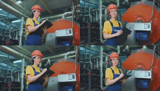 一位年轻的女工程师站在生产车间，记录技术设备的读数。底部视图。现代工业和制造业高清在线视频素材下载