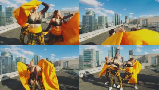 身穿迷彩服的女舞者在屋顶上表演。躲在橙色的织物后面高清在线视频素材下载